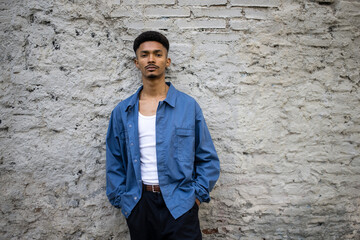 Handsome guy standing on a brick wall looking at camera.