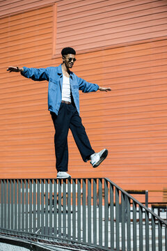 Young relaxed man walking on a handrail.