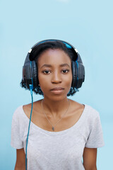 Headphones, audio and portrait of girl in studio for audio streaming, radio or online podcast. Black person, student and relax with technology for media, sound and connection on blue background