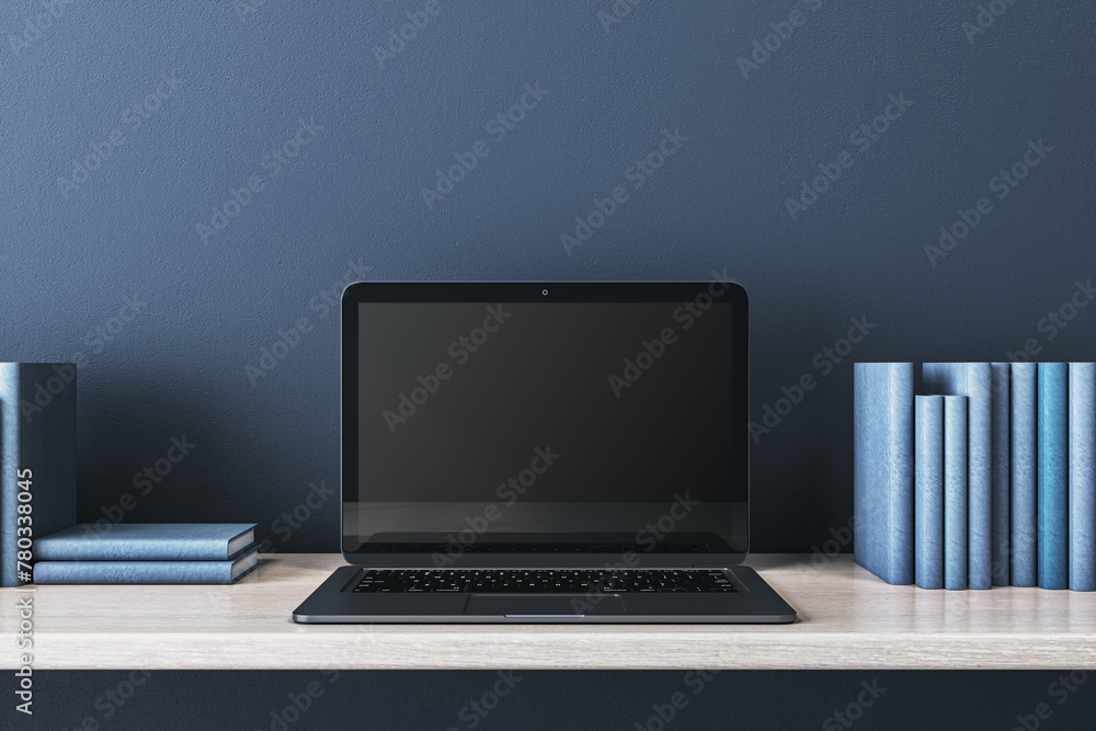 Poster close up of creative wooden designer desk with books and empty mock up laptop screen on blue concret