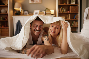 Couple in love under the duvet in bedroom - obrazy, fototapety, plakaty
