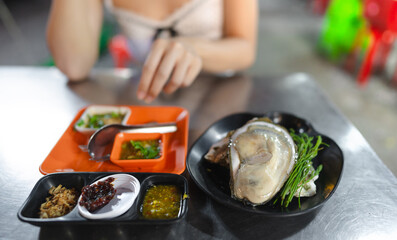 Local raw oyster with thai style seafood sauce at China town asia street food market
