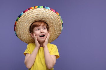 Surprised boy in Mexican sombrero hat on violet background, space for text