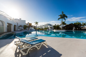 swimming pool with empty sun loungers