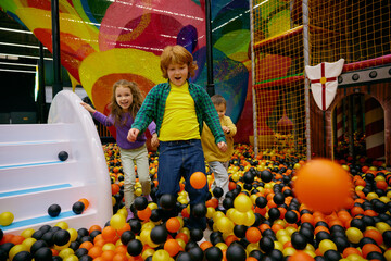 Amazed carefree preschool children playing together on indoor playground - 780341203