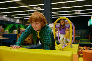 Happy children passing road of obstacles on indoor playground - 780341285
