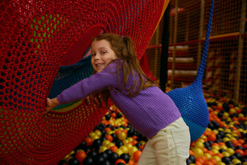 Little preschool girl feeling joyful and playful spending time at game center
