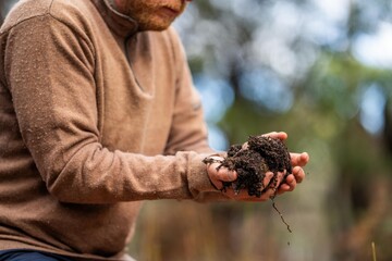 soil scientist agronomist farmer looking at soil samples and grass in a field in spring. looking at growth of plants and soil health