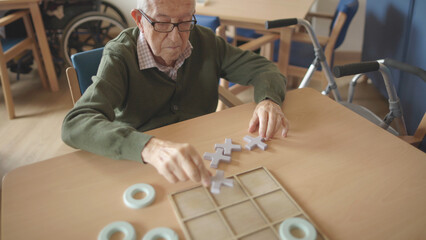 elderly man placing a board game tile in a retirement home