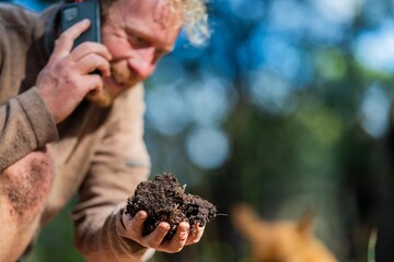 university student conducting research on forest health. farmer collecting soil samples in a test tube in a field. Agronomist checking soil carbon and plant health on a farm