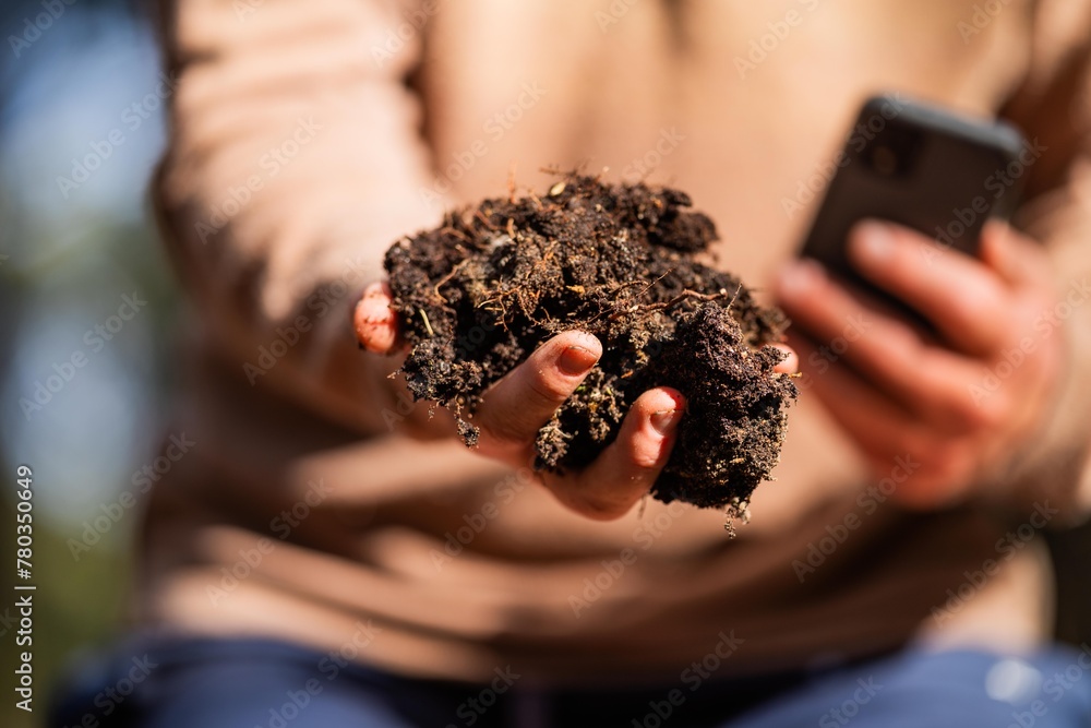 Wall mural farmer hold soil in hands monitoring soil health on a farm. conducting soil tests