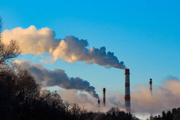 View of tall chimneys smoking in puffs of steam, industrial landscape