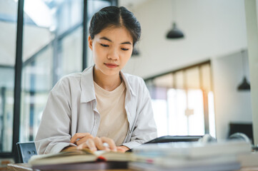 Young Asian college student doing report, drawing on tablet in cafe. Communicating and researching online.