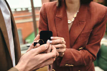 A person on bended knee offers a ring to their partner, capturing a heartwarming proposal. - obrazy, fototapety, plakaty