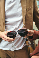 A stylish man with a glass in each hand filled with red wine, showcasing elegance and sophistication