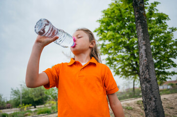 Beautiful child drinking water in the park.