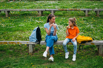 Beautiful children eating a sandwich and a banana in the park.