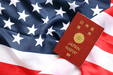 Japan passport on United States national flag background close up. Tourism and diplomacy concept