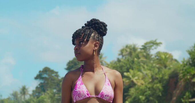 A black girl in a swimsuit enjoys a day at a tropical island beach.