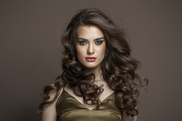 Lovely young brunette female model with long brown wavy hair and makeup closeup portrait