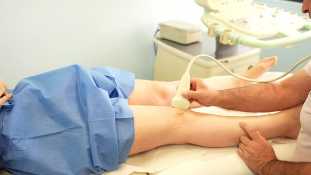 Physiotherapist performing knee ultrasound on his patient at his clinic. Closeup