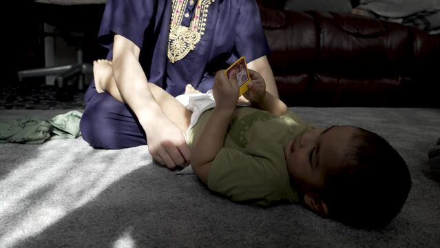 Mother changes her small toddler's diaper, symbolizing the essence of motherhood and nurturing during infancy, a pivotal time in a child's growth and development. slow motion shot, low angle