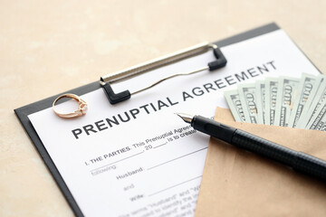 Prenuptial agreement and wedding ring on table. Premarital paperwork process in USA close up