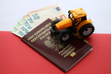 Red polish passport and yellow tractor on euro money and smooth red and white flag of Poland close up