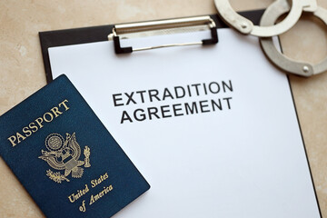 Passport of United States and Extradition Agreement with handcuffs on table close up