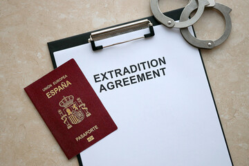 Passport of Spain and Extradition Agreement with handcuffs on table close up