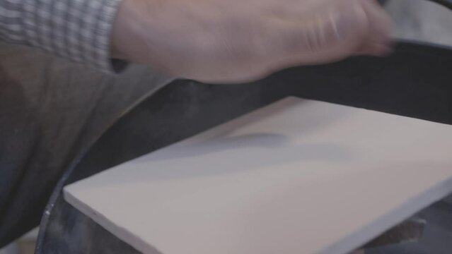 manos trabajando sobre ceramica raspando y quitando pintura blanca