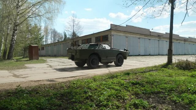 A green, mid-20th century Soviet armored reconnaissance and patrol vehicle in motion, kicking up dust, designed for military reconnaissance.