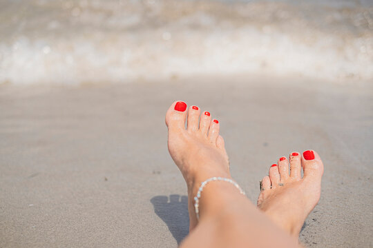 Vacation holidays. Woman feet closeup with red painted nails of girl relaxing on sunny summer day.