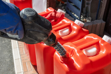 Refueling a red polyethylene tank with kerosene.