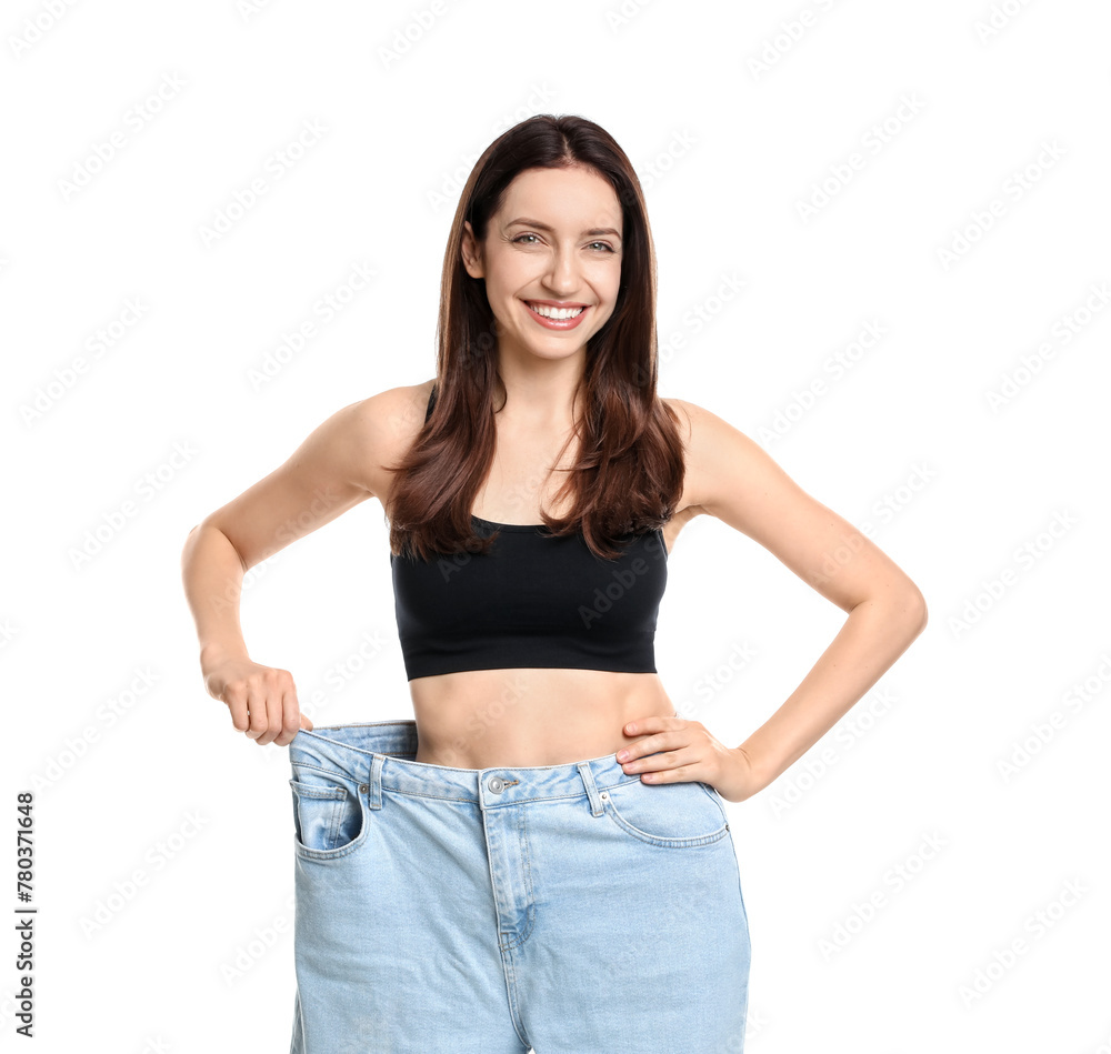 Wall mural Happy young woman in big jeans showing her slim body on white background