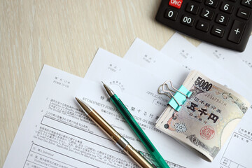 Naklejka premium Japanese tax forms lies on table with calculator, pen and japanese yen money bills roll close up