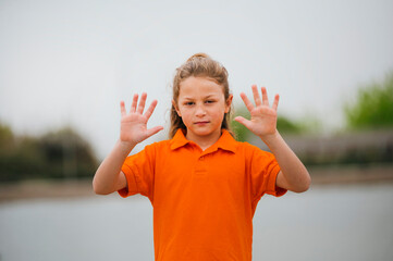 Portrait of a boy with long hair and showing hands.
