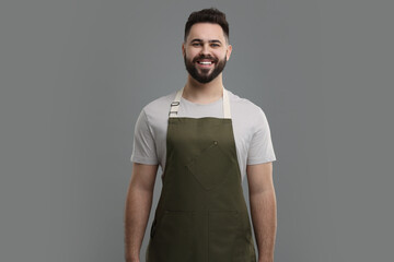Smiling man in kitchen apron on grey background. Mockup for design