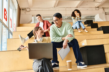 Multicultural students sit on bleachers, focused on laptops, in an educational setting at a university or high school.