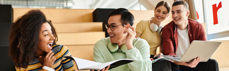 A multicultural group of students sitting together, including an African American girl, engaged in...