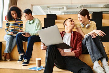 Multicultural group of young adults sitting on bench, engrossed in laptops, collaborating on...