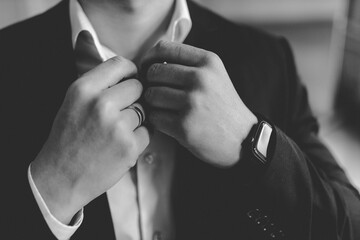 groom in a suit adjusts his shirt collar