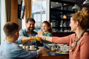 Happy family having fun and toasting during breakfast in  hotel restaurant. - obrazy, fototapety, plakaty