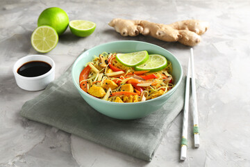 Stir-fry. Delicious cooked noodles with chicken and vegetables in bowl served on gray textured table