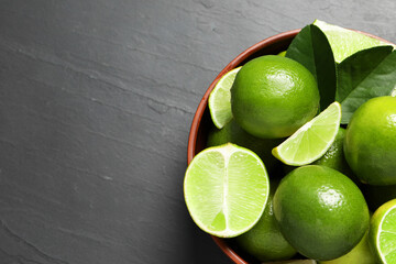 Fresh ripe limes in bowl on black table, top view. Space for text