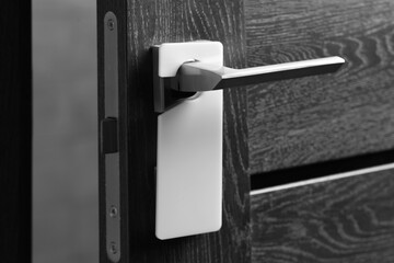 Wooden door with blank hanger on metal handle, closeup