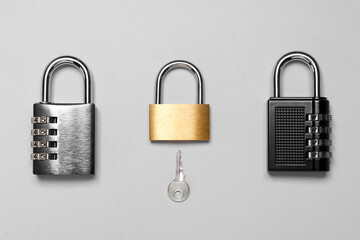 Different padlocks and key on grey background, flat lay