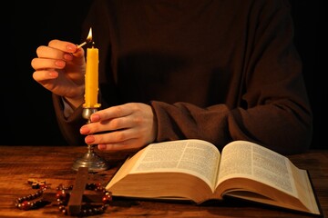 Woman lighting candle at table with Bible, closeup