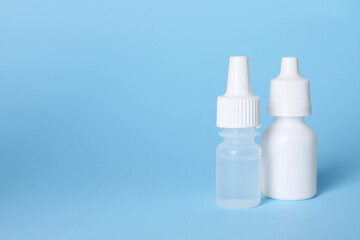 Bottles of medical drops on light blue background, space for text
