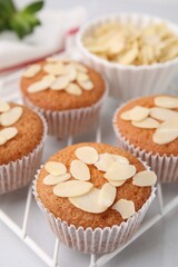 Muffins with fresh almond flakes on white table, closeup